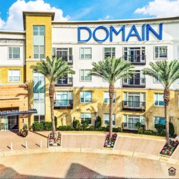 a building with a walkway and palm trees in front of it